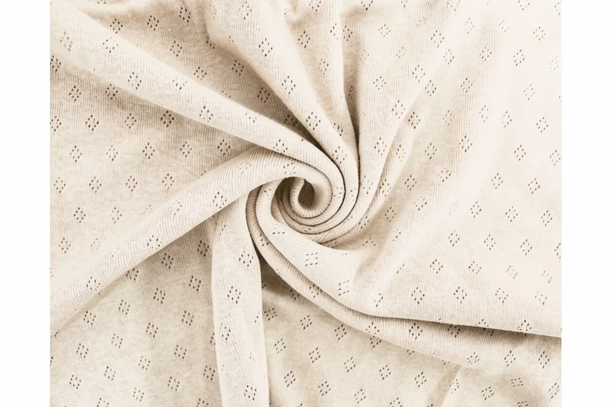 Pointelle knit fabric in cream cotton with delicate openwork lace pattern, manufactured at Apex Corporation knitwear factory in Karachi Pakistan